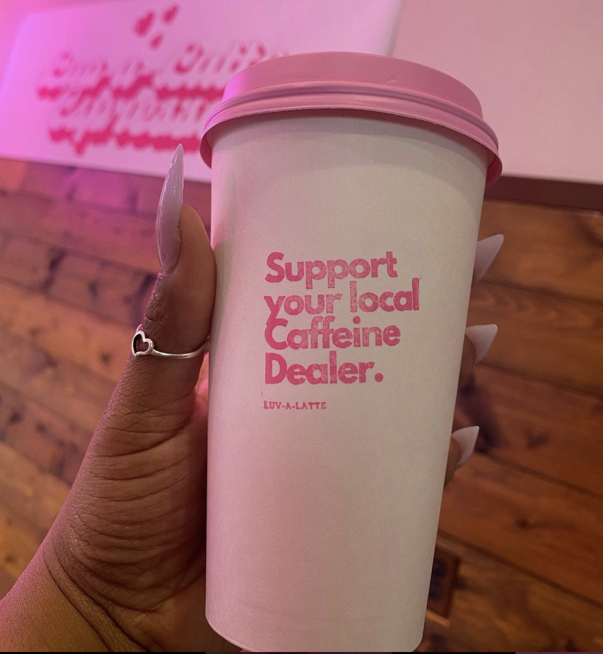 coffee cup with a pink lid with a cup that reads "support ya local caffeine dealer"